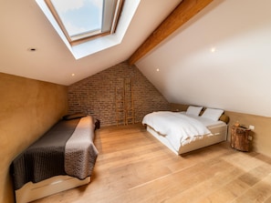A loft bedroom with a sloped ceiling, exposed brick wall, and a skylight. - Bertrix Charming 2-bedroom Holiday Home (Bertrix)