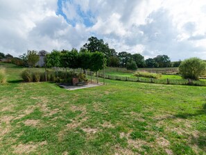 A grassy field with a small garden area, a wooden fence, and trees in the background. - Bertrix Charming 2-bedroom Holiday Home (Bertrix)