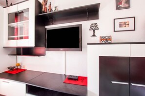 A modern kitchen with a flat-screen TV, built-in cabinets, and decorative items. - Refreshing Apartment in Omis With Balcony (Omis)