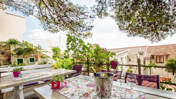An outdoor dining area with wooden tables, chairs, and potted plants. - Refreshing Apartment in Omis With Balcony (Omis)