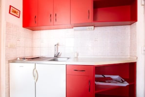 A kitchen with red cabinets, a white countertop, a built-in dishwasher, and a tiled backsplash. - Refreshing Apartment in Omis With Balcony (Omis)