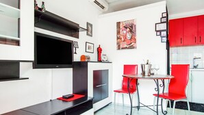 A modern kitchen with red chairs, a dining table, and a flat-screen TV mounted on the wall. - Refreshing Apartment in Omis With Balcony (Omis)