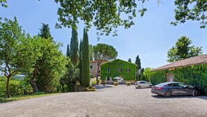 A gravel driveway leading to a house with a green roof, parked cars, and surrounding trees. - Escape Near San Gimignano (San Gimignano)