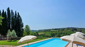 A swimming pool with lounge chairs and umbrellas, surrounded by stone tiles and greenery. - Escape Near San Gimignano (San Gimignano)