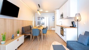 Um apartamento moderno com sala de jantar, cozinha compacta e área de estar.