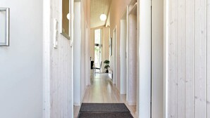 Un couloir aux murs en bois, un paillasson noir et une porte au fond.