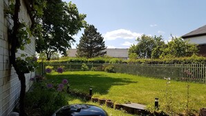 A backyard with a barbecue grill, a wooden fence, and a garden with various plants and flowers. - Ruhlen: Schneifel Escape (Auw bei Prüm)