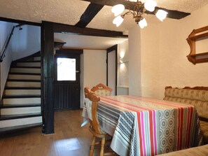 Um quarto com escada de madeira, uma mesa de jantar com toalha listrada e um sofá estampado.