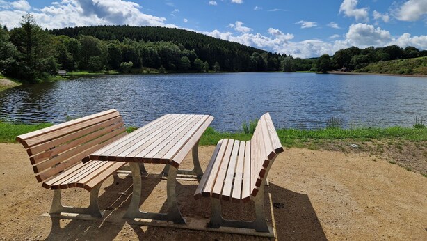 Two wooden benches facing a lake with a forested hill in the background. - Ruhlen: Schneifel Escape (Auw bei Prüm)