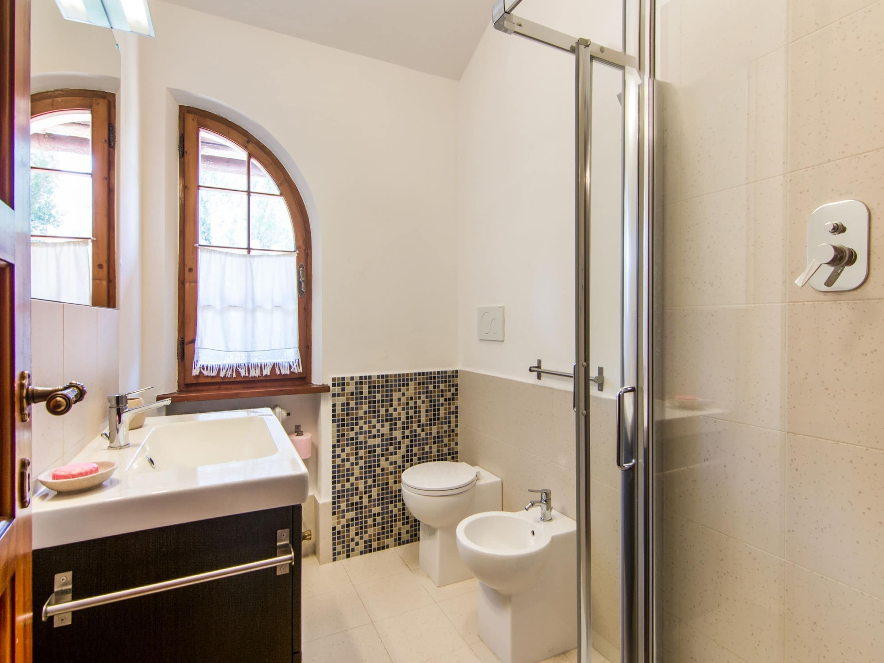 Une salle de bain avec une douche à parois de verre, un lavabo, des toilettes et un bidet.