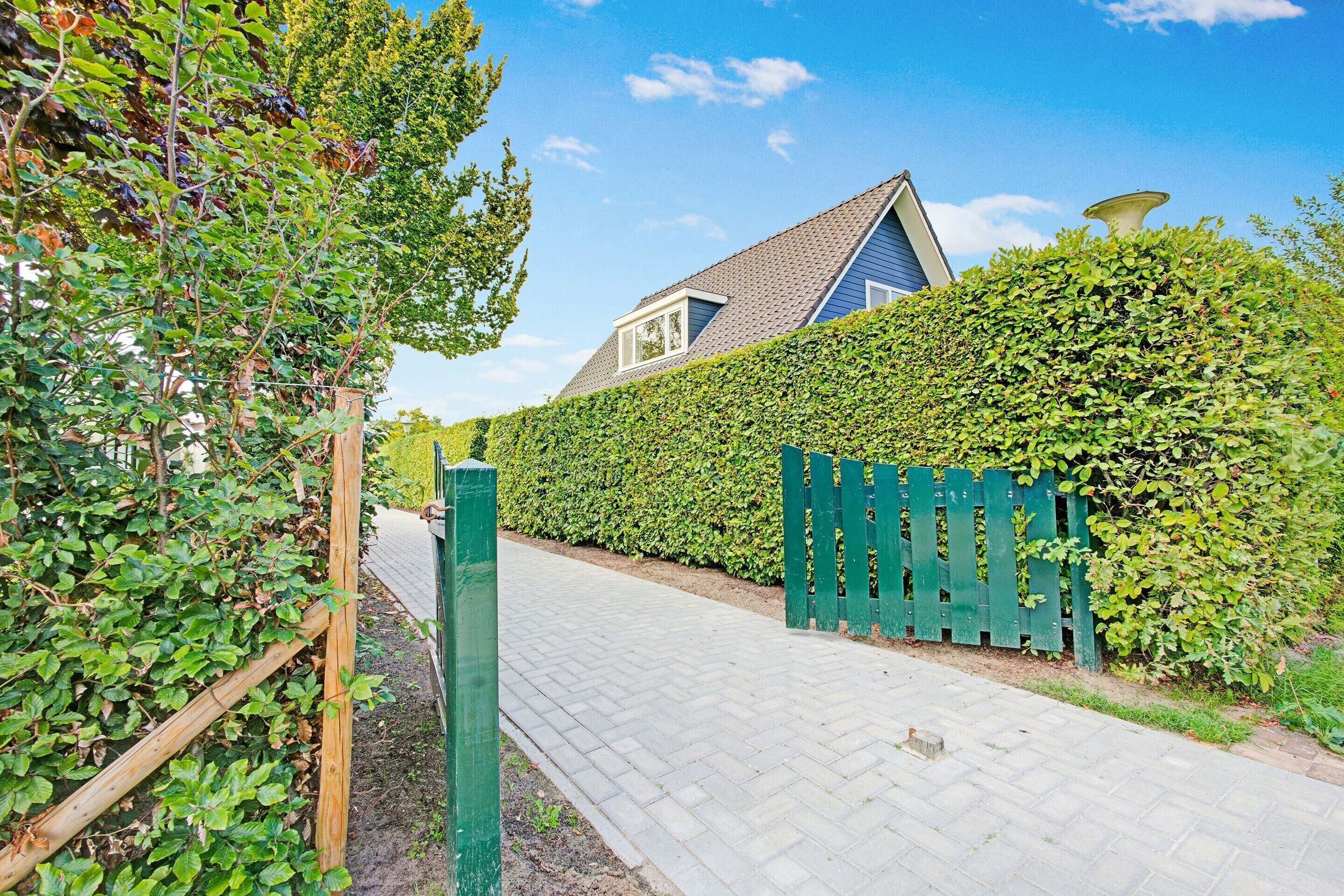 A pathway leading to a house with a blue roof and a green fence.