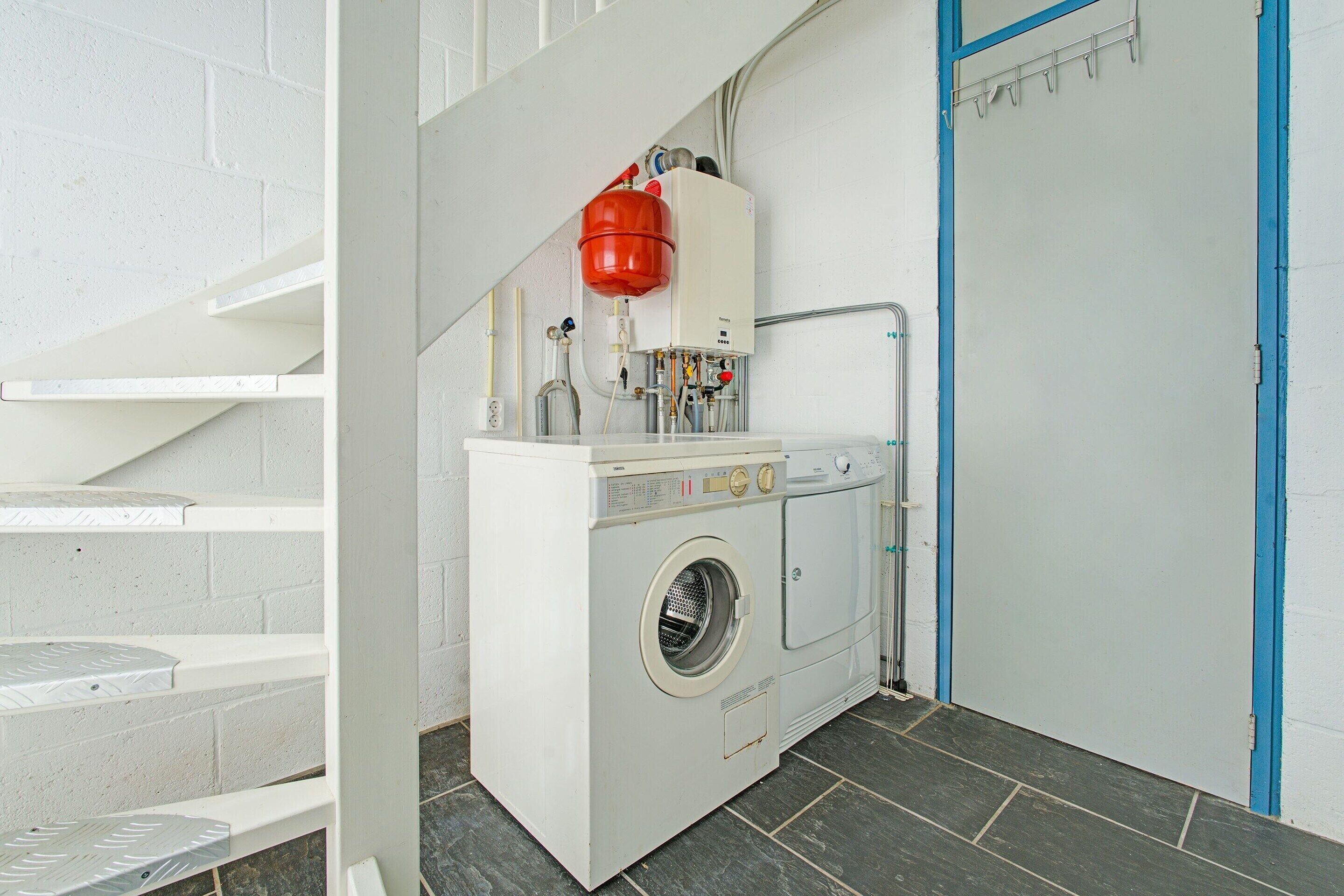 A laundry room with a washing machine, a dryer, and a red fire extinguisher mounted on the wall.