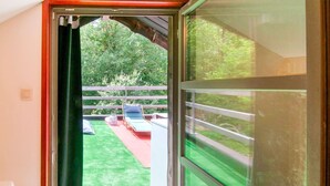 Un balcon avec une pelouse verdoyante, un lit et une chaise.