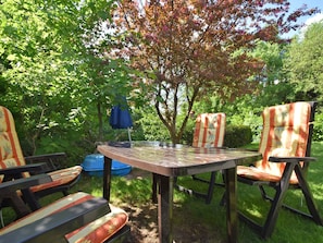 Un espace extérieur aménagé avec une table et des chaises, entouré d’une végétation luxuriante et d’arbres.