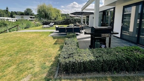 Eine moderne Außenpatio mit Grill, Sitzbereich und Blick auf das Haus.