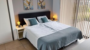 Ein modernes Schlafzimmer mit einem großen Bett, zwei Nachttischen, einem Kopfteil und Bildern an der Wand.