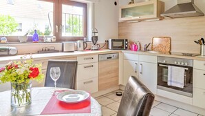 Una cocina moderna con comedor, que incluye microondas, tostadora, hervidor y pileta.