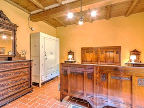 A room with a wooden dresser, a white cabinet, and a wooden vanity with mirrors.