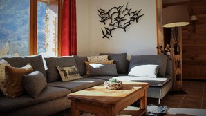 A cozy living room with a sectional sofa, a wooden coffee table, and a wall art piece. - Chalet Chocolat chaud 4 rooms - 90m², sleeps 7 in the heart of Belleville (st martin de Belleville)