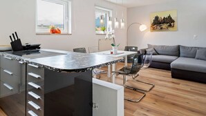 A modern kitchen with a marble countertop, a dining area with chairs, a sofa, and a painting on the wall. - Apartment Innsbruck Near Bergisel Ski Jump (Innsbruck)