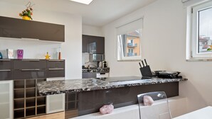 A modern kitchen with dark cabinetry, a granite countertop, and a window with a view of buildings. - Apartment Innsbruck Near Bergisel Ski Jump (Innsbruck)
