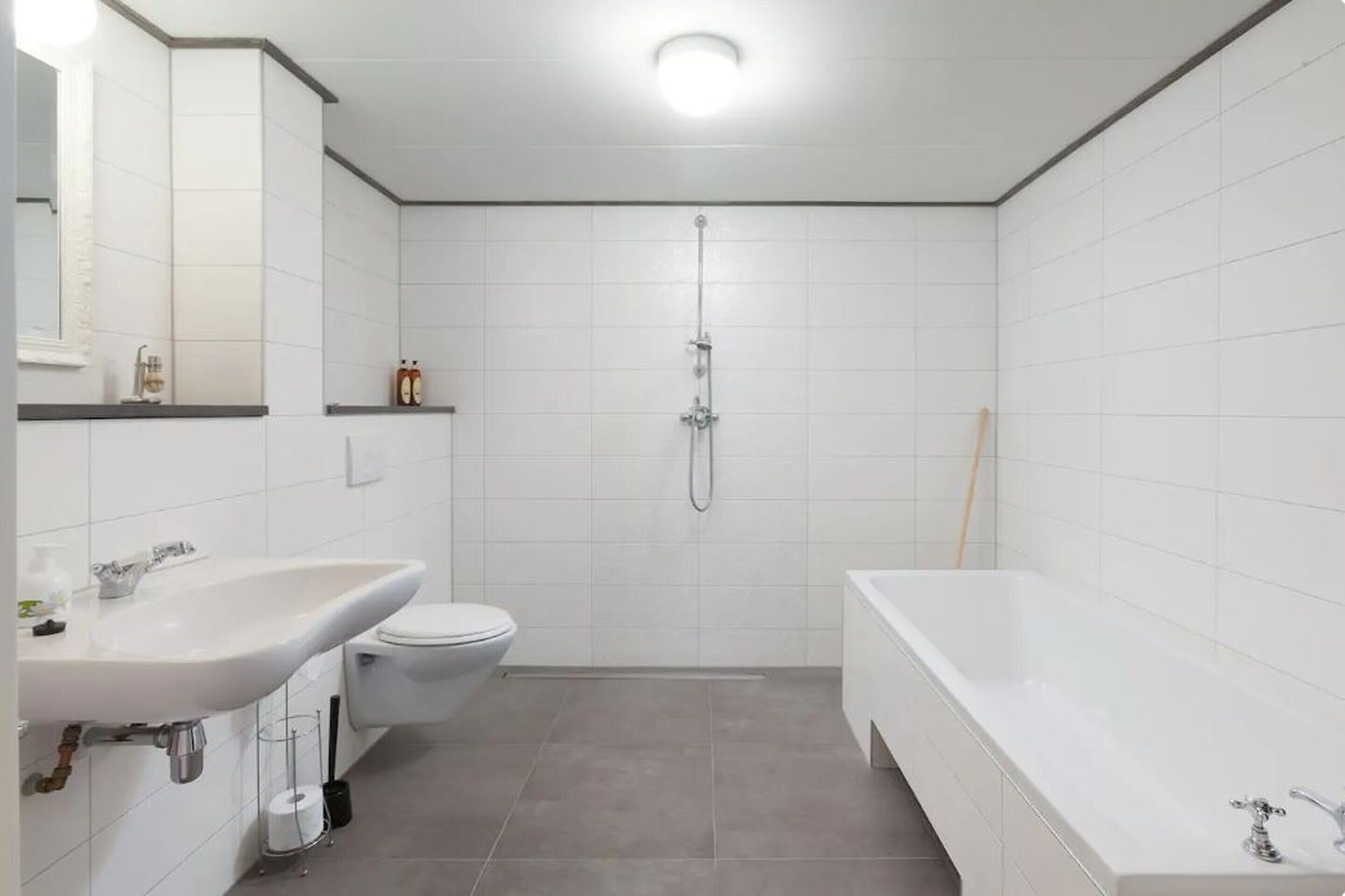 A modern bathroom with a white sink, toilet, shower, and bathtub.