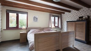 A bedroom with a wooden bed, two bedside tables, a nightstand, a wardrobe, and a window with curtains. - Nice Vacation Home in Horssen With Garden (Horssen)