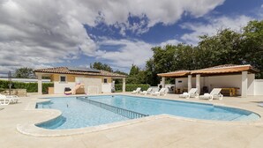 A swimming pool with a tiled deck, lounge chairs, and a covered area with a tiled roof. - Elegant Apartment in Banjole near Fratarski Otok Island (Medulin)