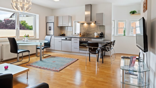 A modern kitchen with a dining area, a TV, and a bookshelf. - Apartment Innsbruck near Bergisel Ski Jump (Innsbruck)