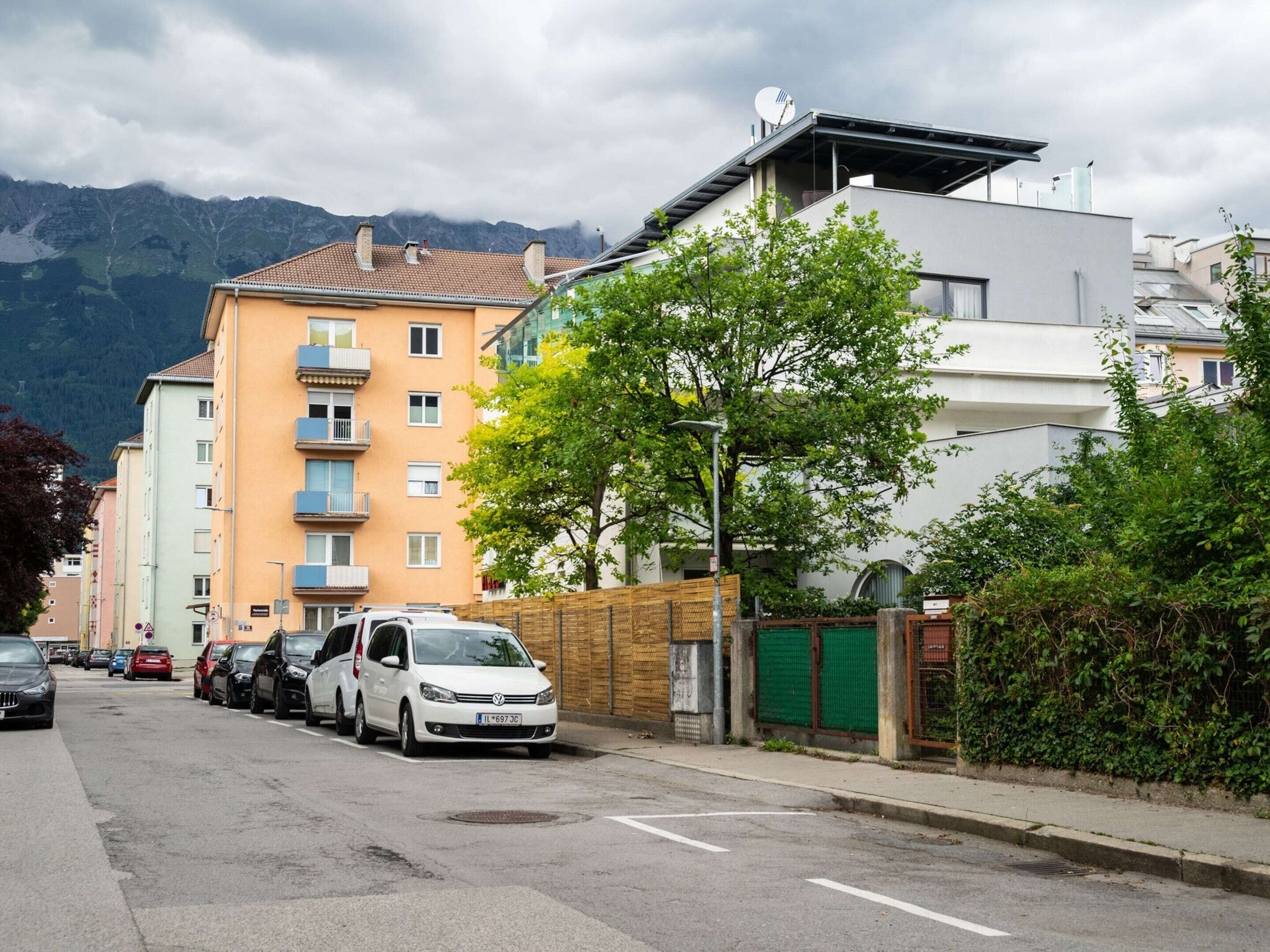 Une rue bordée de voitures garées et d’immeubles à plusieurs étages.