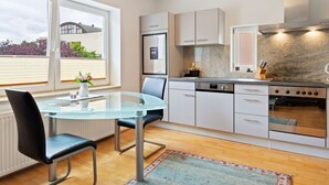 A modern kitchen with a glass dining table, white cabinets, and a stainless steel range hood. - Apartment Innsbruck near Bergisel Ski Jump (Innsbruck)