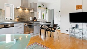 A modern kitchen with granite countertops, stainless steel appliances, and a dining area with a glass table and chairs. - Apartment Innsbruck near Bergisel Ski Jump (Innsbruck)
