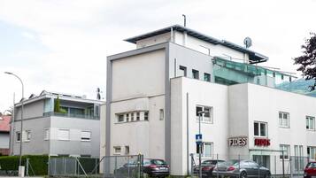 A modern building with a white facade, a glass section on the upper floor, and a sign for 'FIDES' on the right side.