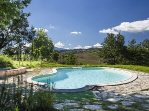 A swimming pool with a stone border and a view of the countryside. - Holiday Home in Cossignano With Pool (Cossignano)