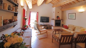 Uma sala de estar acolhedora com vigas de madeira, lareira, televisão e sofá.