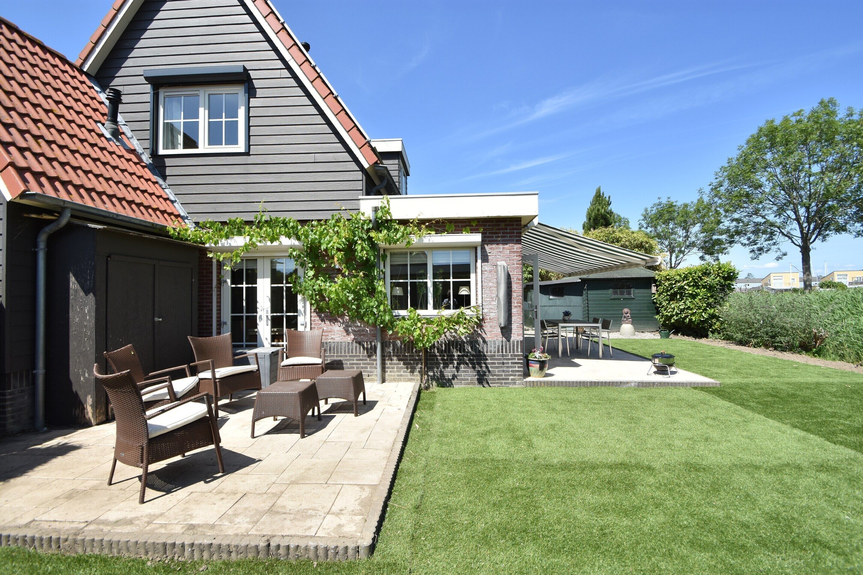 A house with a patio area featuring outdoor furniture and a well-maintained lawn.