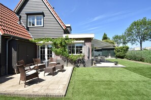 A house with a patio area featuring outdoor furniture and a well-maintained lawn. - Enticing Holiday Home in Oude With Garden (Oude-Tonge)