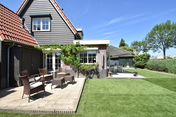 A house with a patio area featuring outdoor furniture and a well-maintained lawn.