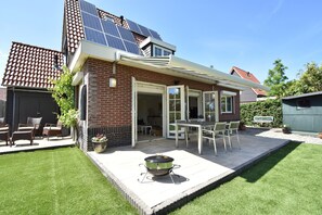 A house with a patio, solar panels, and a barbecue grill. - Enticing Holiday Home in Oude With Garden (Oude-Tonge)