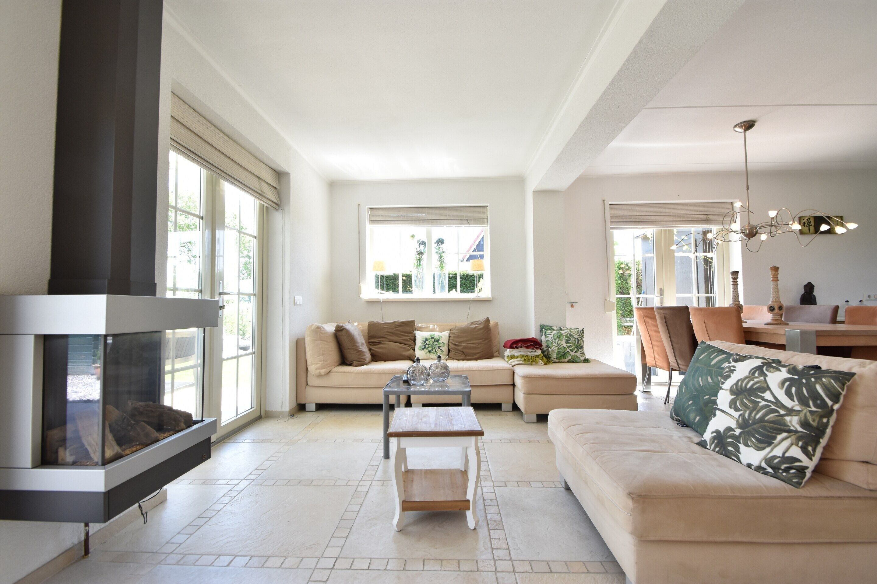 A spacious living room with a fireplace, a sofa, a coffee table, and a dining area with chairs.