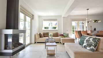 A spacious living room with a fireplace, a sofa, a coffee table, and a dining area with chairs.