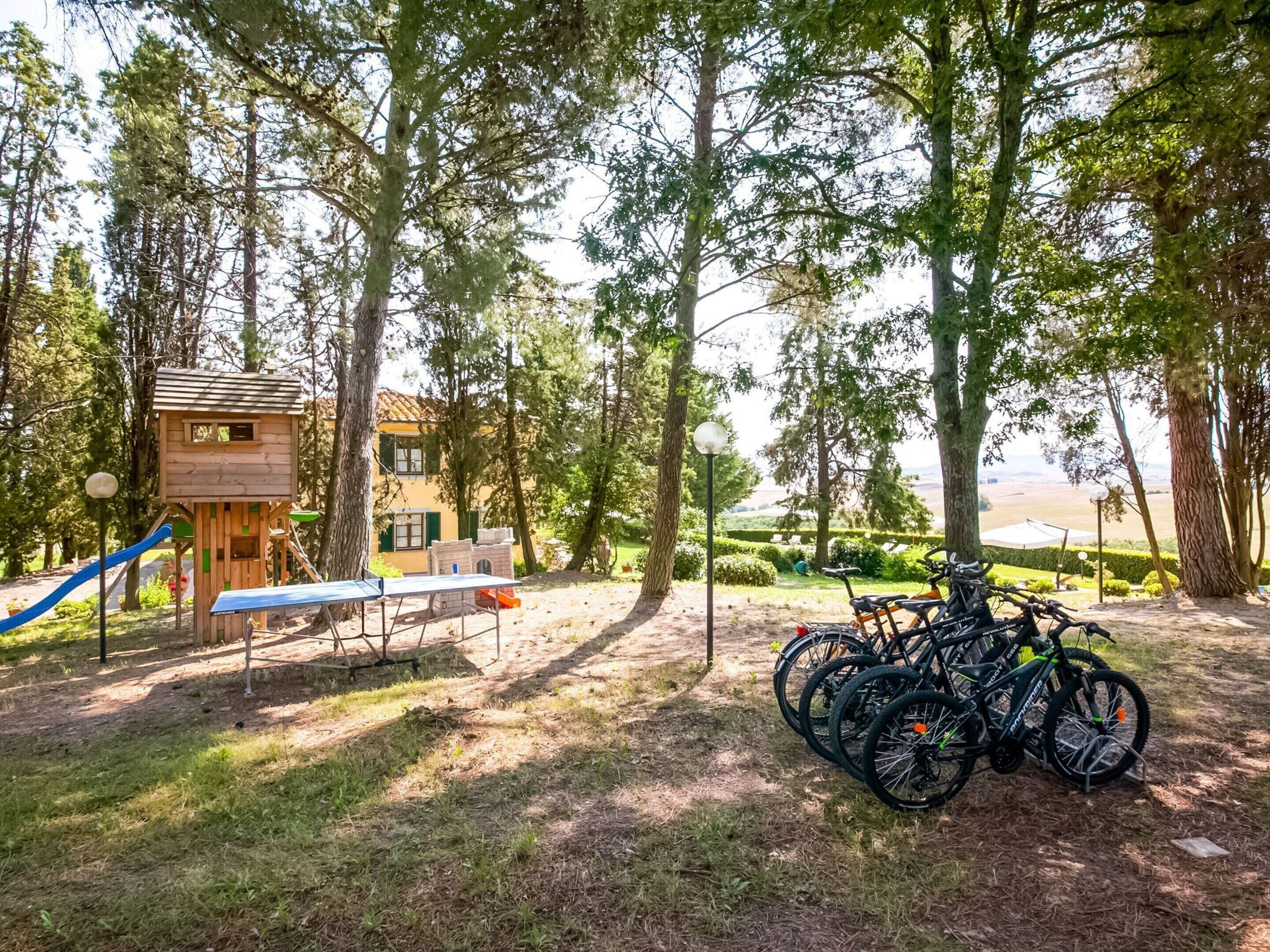 A playground with a slide, a climbing structure, and a table. There are bicycles parked nearby.