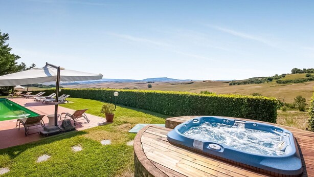 A hot tub on a wooden deck with a view of rolling hills. - Serene Apartment in Orciatico (Lajatico)