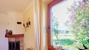 A cozy room with a fireplace, a window with a view of greenery, and a decorative item on the windowsill. - Holiday Home in Porcheresse Daverdisse (Daverdisse)