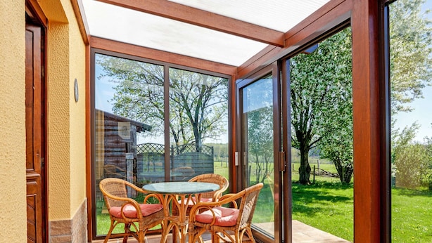 A sunlit patio with wicker furniture and a glass door leading to a green landscape. - Holiday Home in Porcheresse Daverdisse (Daverdisse)