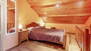 A bedroom with a wooden ceiling, a bed, a nightstand, a mirror, and a small table. - Holiday Home in Porcheresse Daverdisse (Daverdisse)