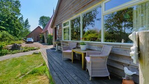 A wooden deck with wicker furniture and a potted plant. - Enticing Holiday Home in Eastermar near Burgumer Mar Lake (Eastermar)