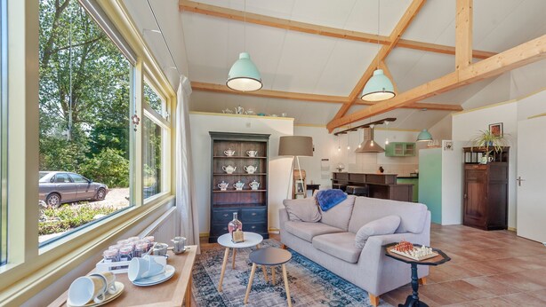 A spacious living room with a sofa, a coffee table, and a dining area with a table set for tea. - Enticing Holiday Home in Eastermar near Burgumer Mar Lake (Eastermar)