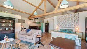 A spacious living area with a high ceiling, wooden beams, a sofa, a dining table, and a kitchen in the background. - Enticing Holiday Home in Eastermar near Burgumer Mar Lake (Eastermar)