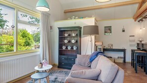 A cozy living room with a sofa, a chessboard, a small table with a lamp, and a bookshelf filled with decorative items. - Enticing Holiday Home in Eastermar near Burgumer Mar Lake (Eastermar)